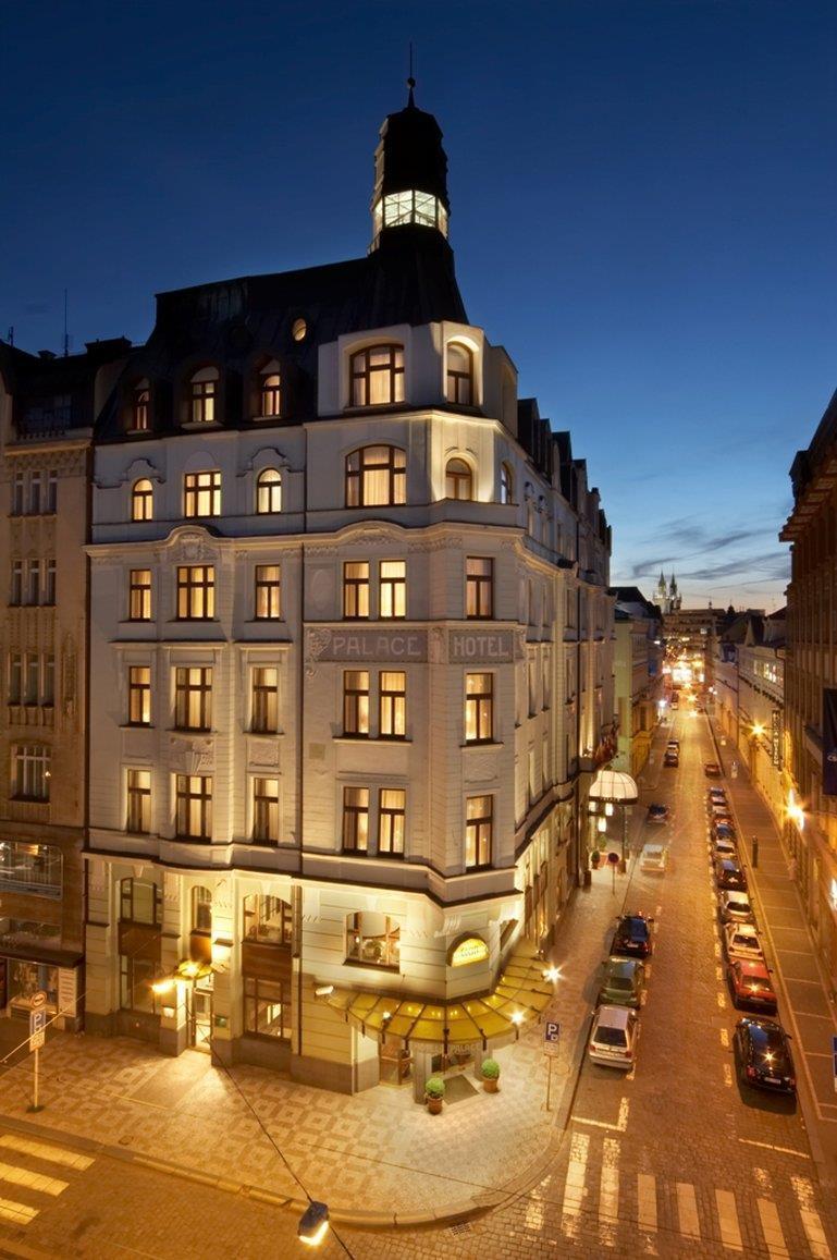 Art Nouveau Palace Hotel Praga Esterno foto The photo shows a beautifully illuminated hotel building at dusk. The architecture has a classic style, featuring several large windows with warm lighting that gives a welcoming appearance. The hotel bears the name "Palace Hotel" prominently displaye