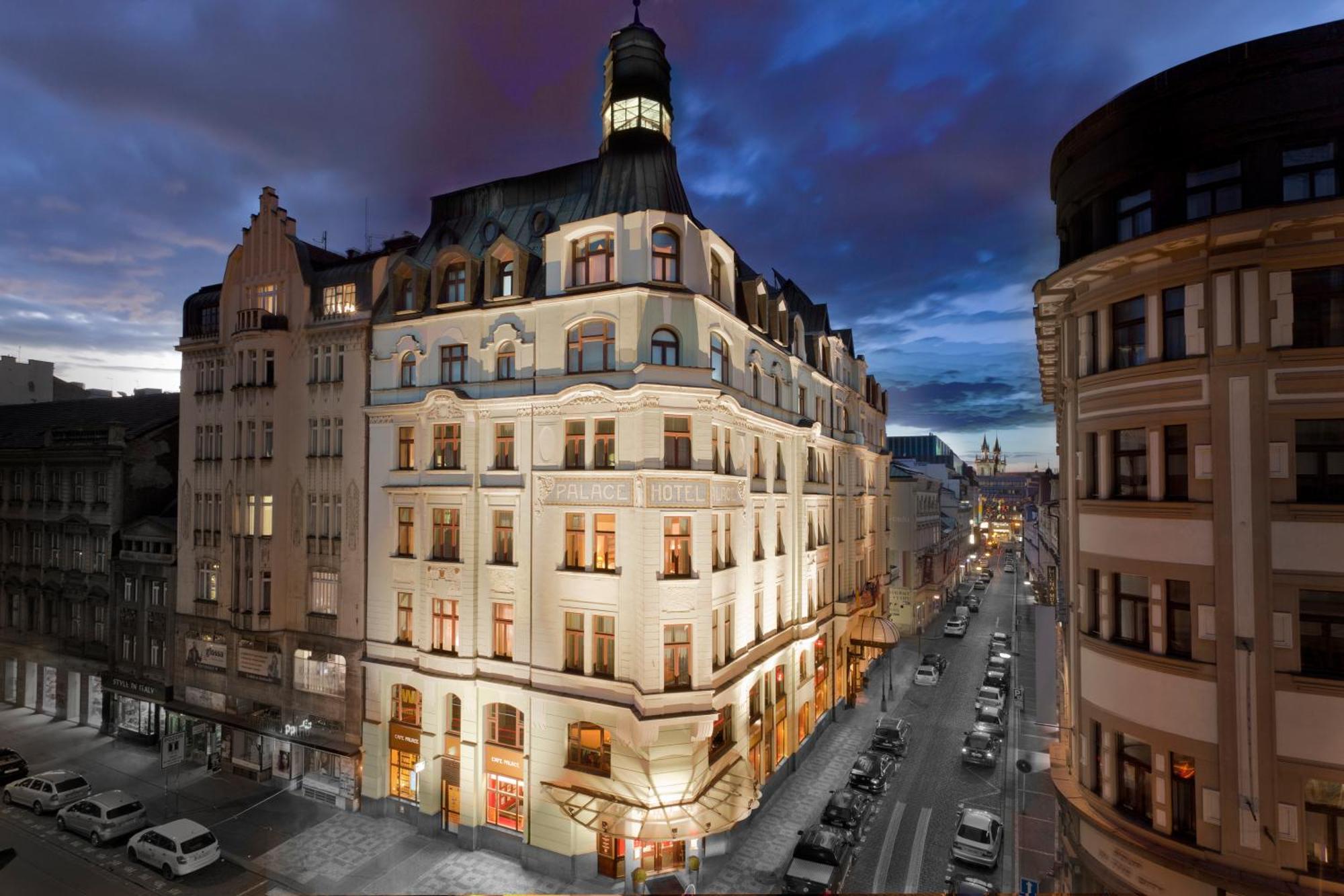 Art Nouveau Palace Hotel Praga Esterno foto The image shows a beautifully designed building at dusk. The structure features an elegant architectural style, with distinct elements like a tower or cupola at the top. The facade is illuminated, highlighting the intricate details of the design. The