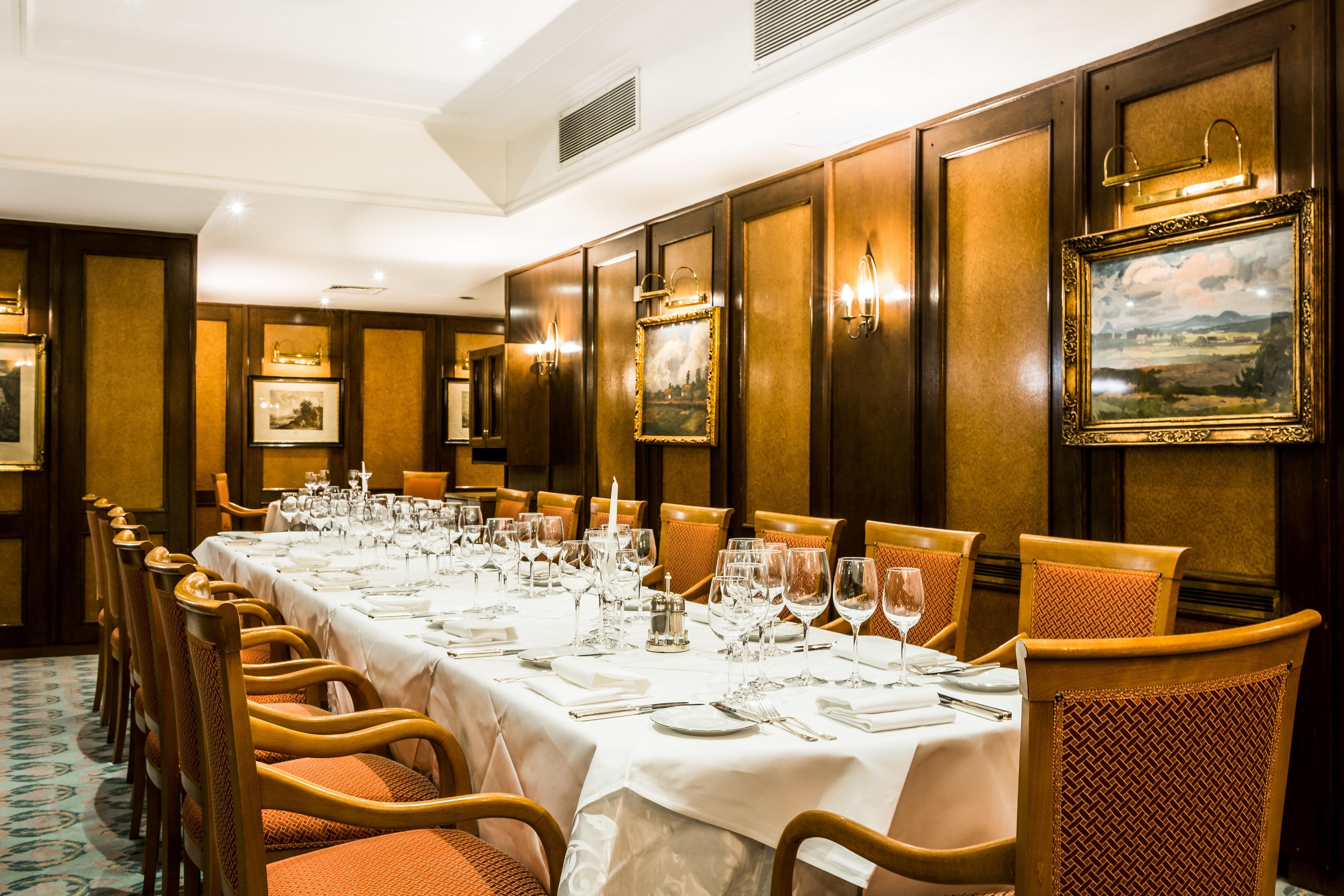 Art Nouveau Palace Hotel Praga Esterno foto The photo depicts an elegant dining room arranged for a formal meal. There is a long table set with white tablecloths, and it is adorned with multiple place settings, including plates, cutlery, and wine glasses. The chairs are upholstered in a warm o
